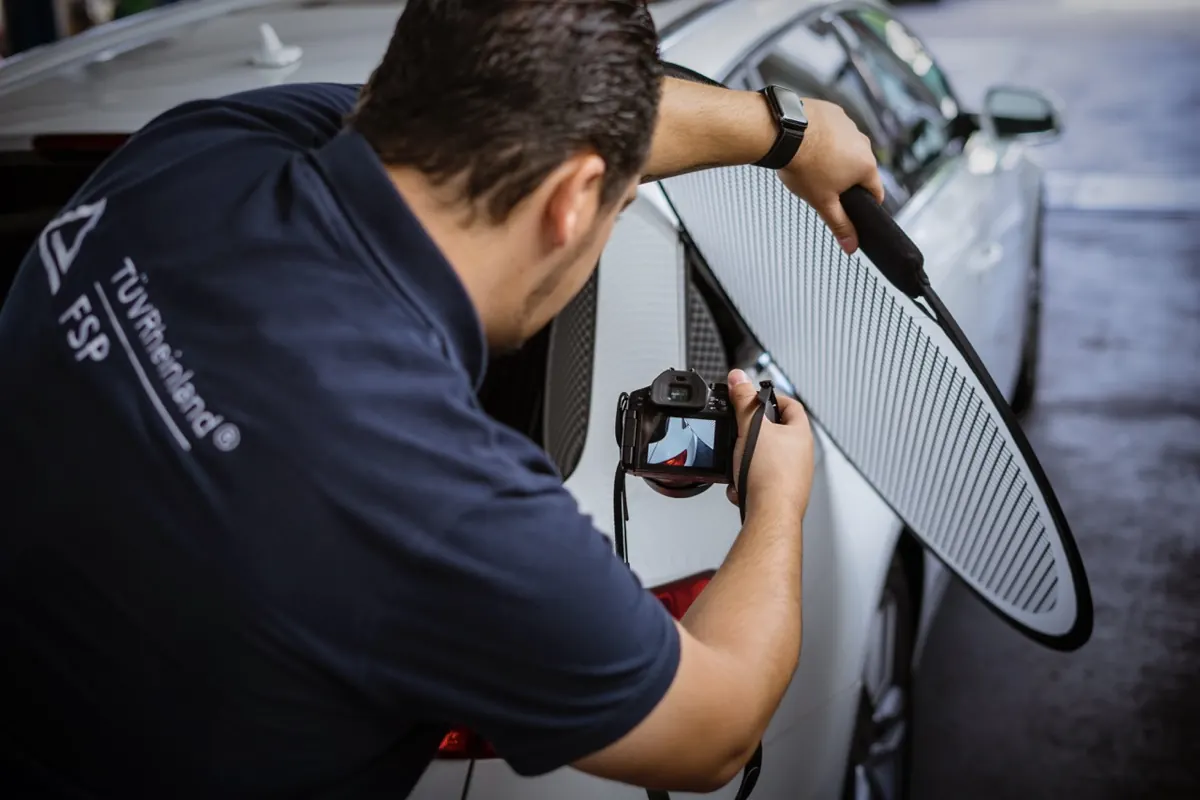Gutachter fotografiert einen Fahrzeugschaden mit Diffusor